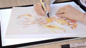 A caption from a video tutorial on the process of colouring a manga character with markers.